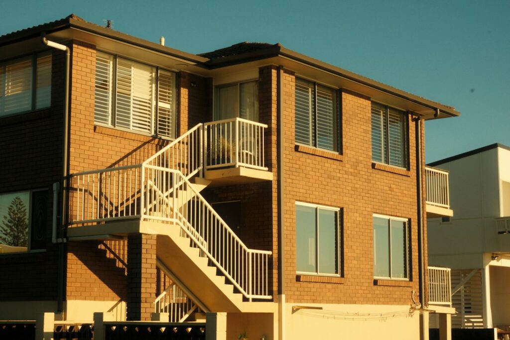 Red brick residential apartment building with a white outdoor staircase and rows of windows