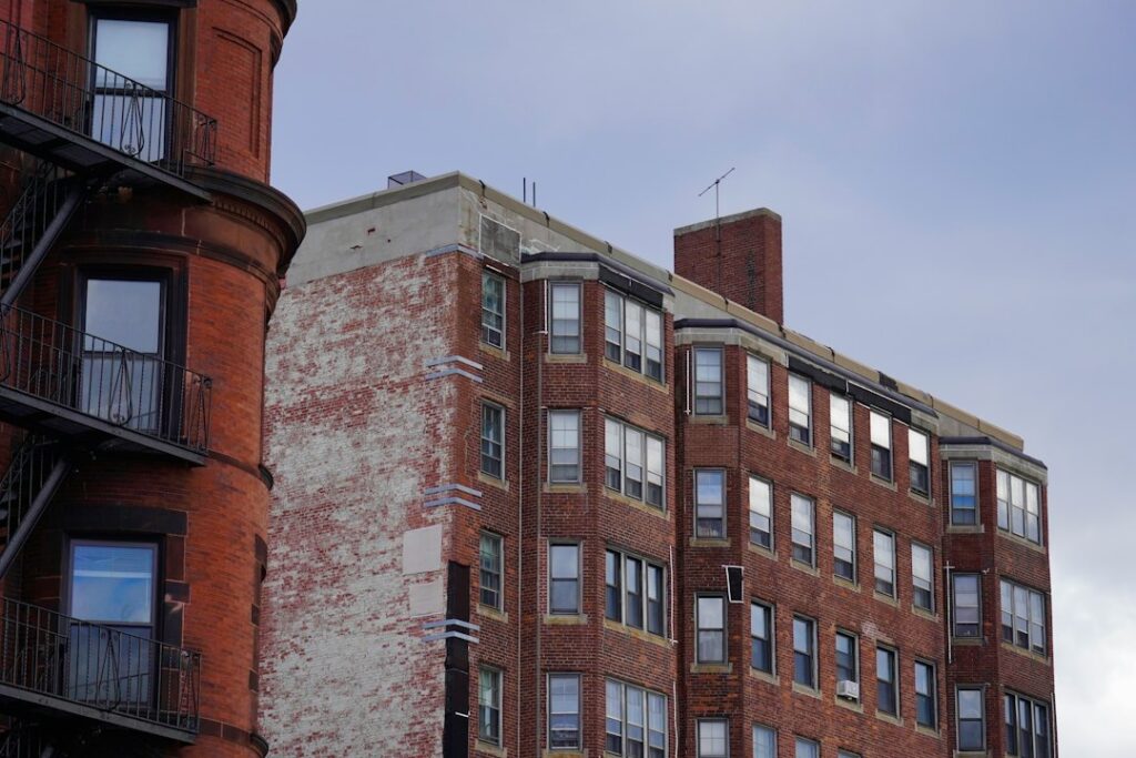 Multistory brick apartment buildings with rows of windows set against a cloudy sky