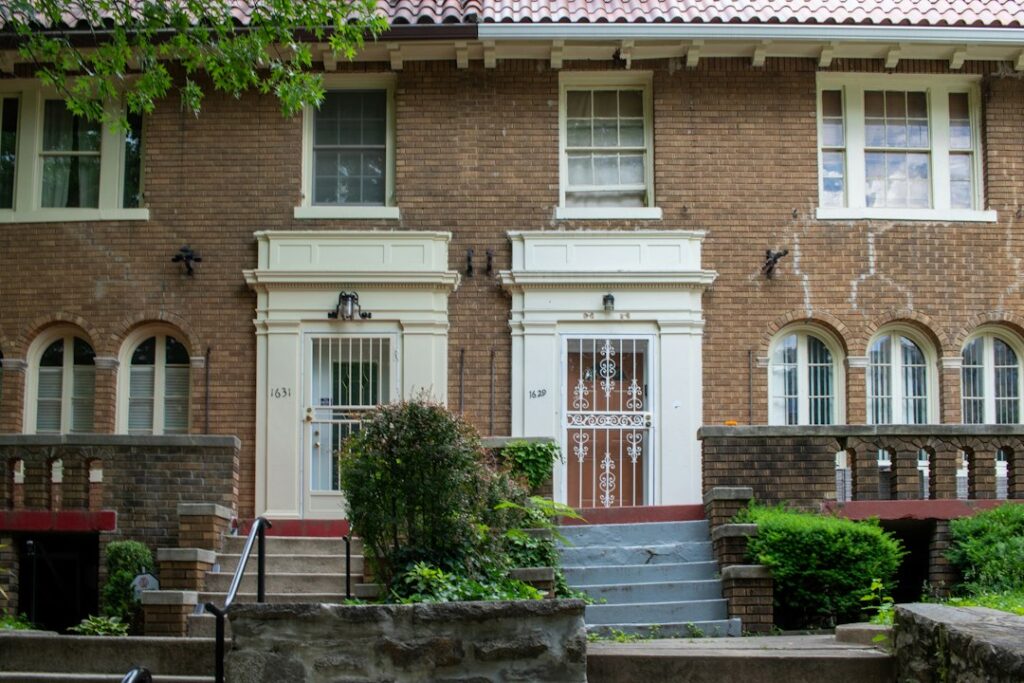 Older brick multifamily building with concrete steps leading up to its front entrance