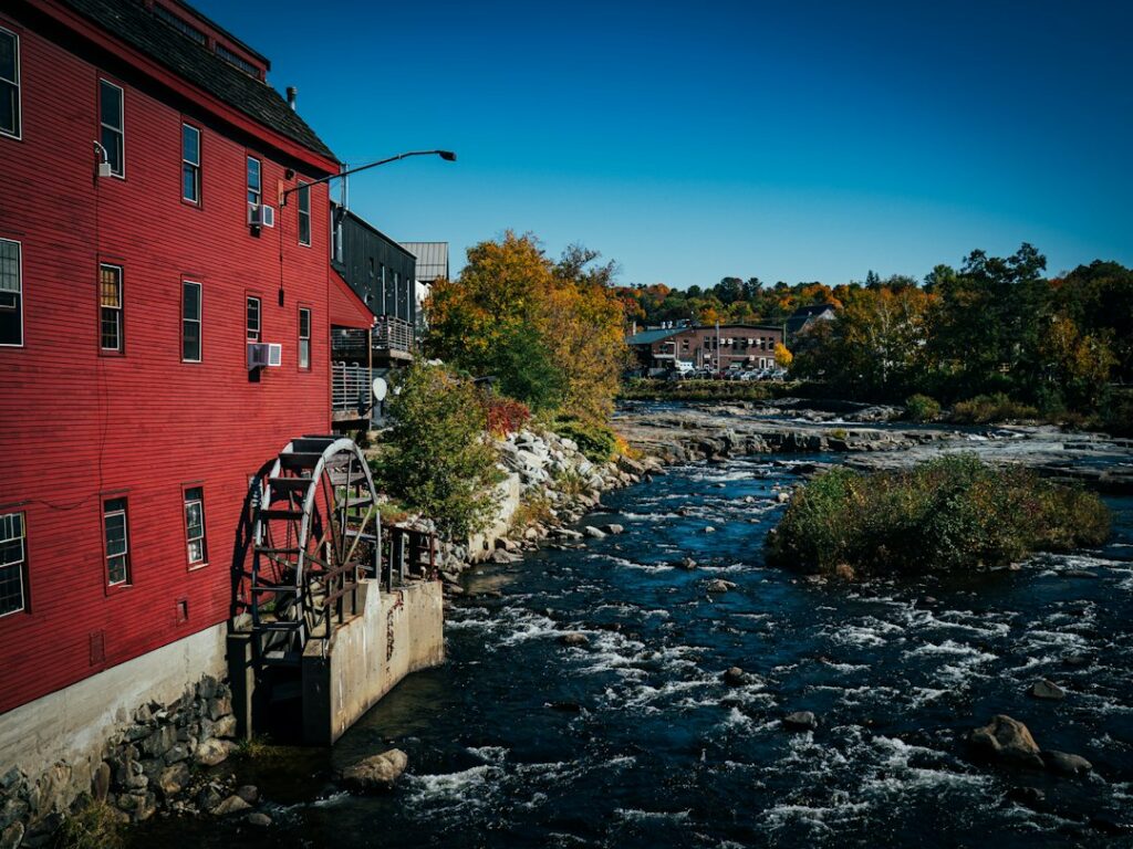 Historic red mill building beside a river in New Hampshire, typical of regional mill architecture