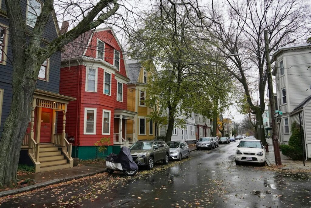 Row of older wooden residential buildings lining a city street on a rainy day